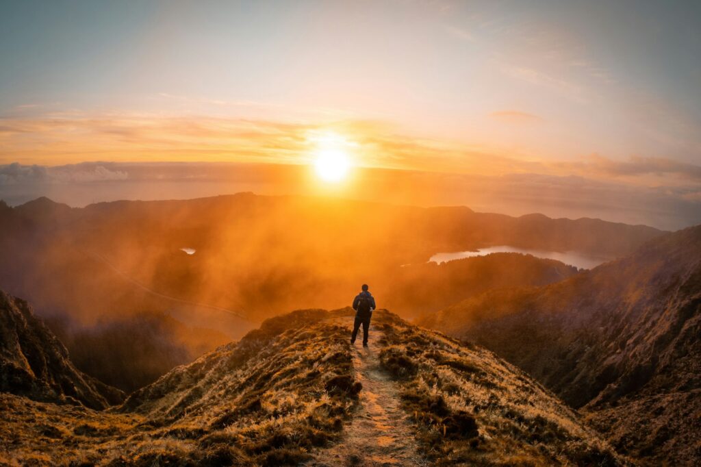 Man standing on the edge of the cliff with a golden sunset background